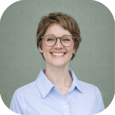 Lauren Charis Athon, Director at Uplift, smiling, wearing glasses and a light blue collared shirt